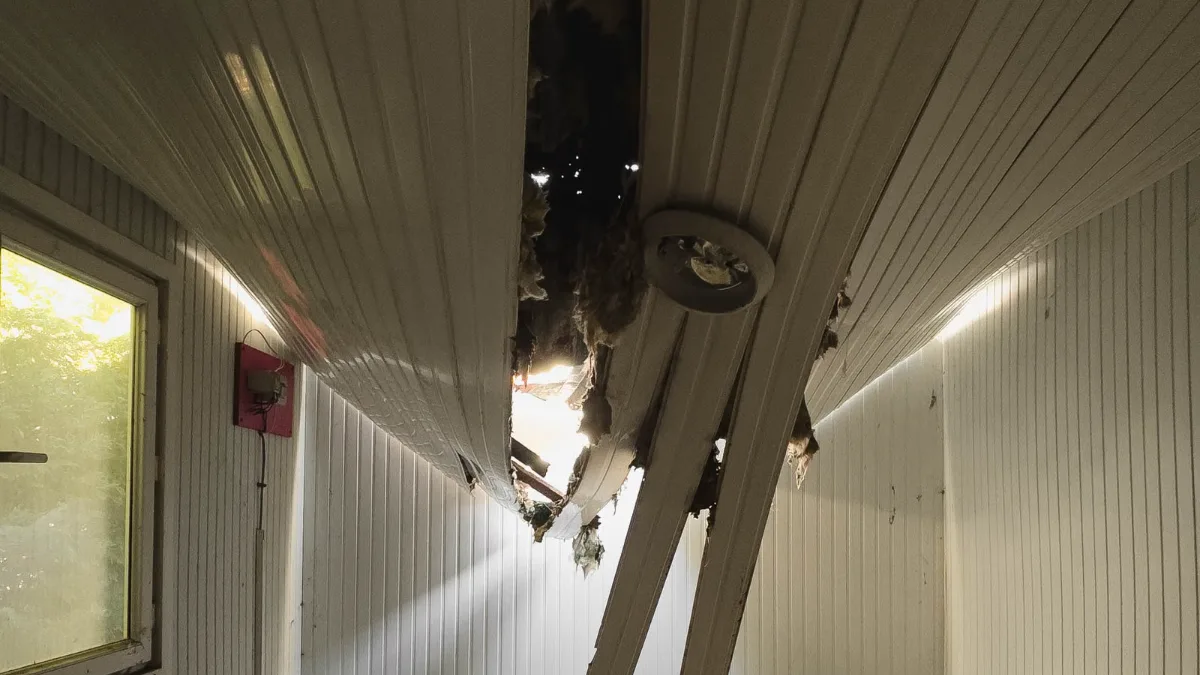 Water-damaged ceiling sagging and split open in a room