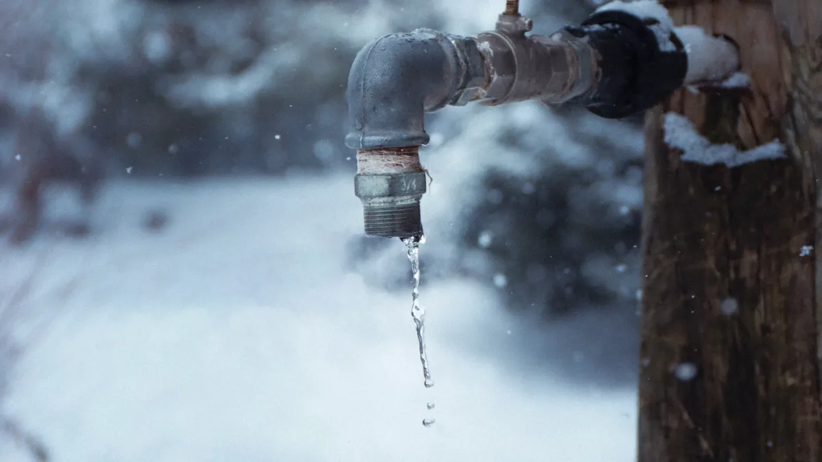 Outdoor water faucet frozen and dripping in the snow